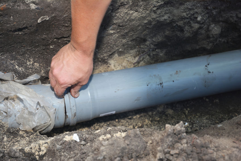 Worker connecting a replacement sewer pipe