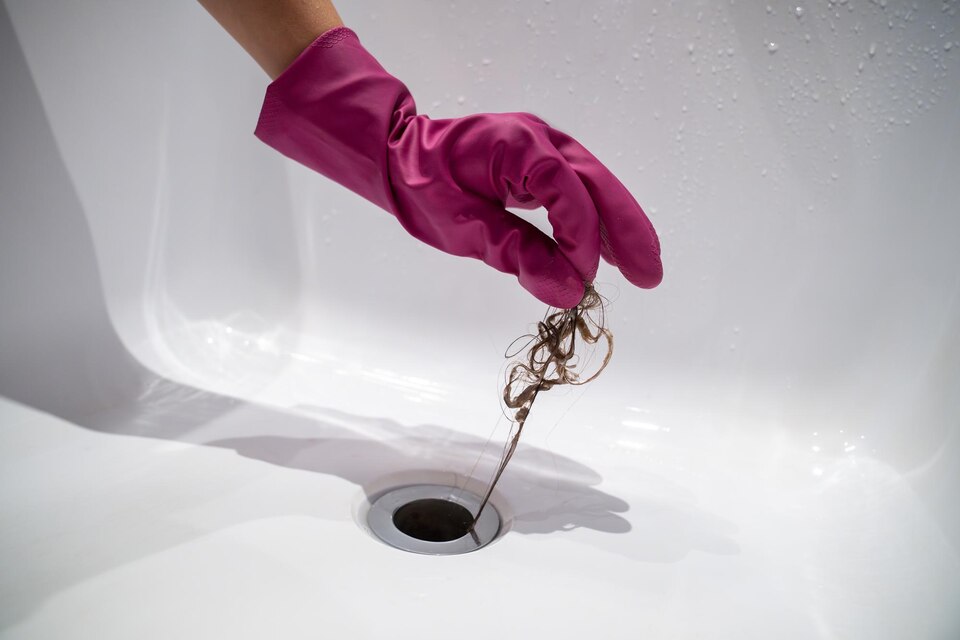 Hair being removed from a bathtub drain