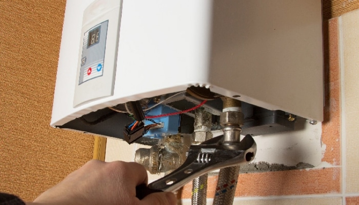 Technician servicing a compact water heater connection