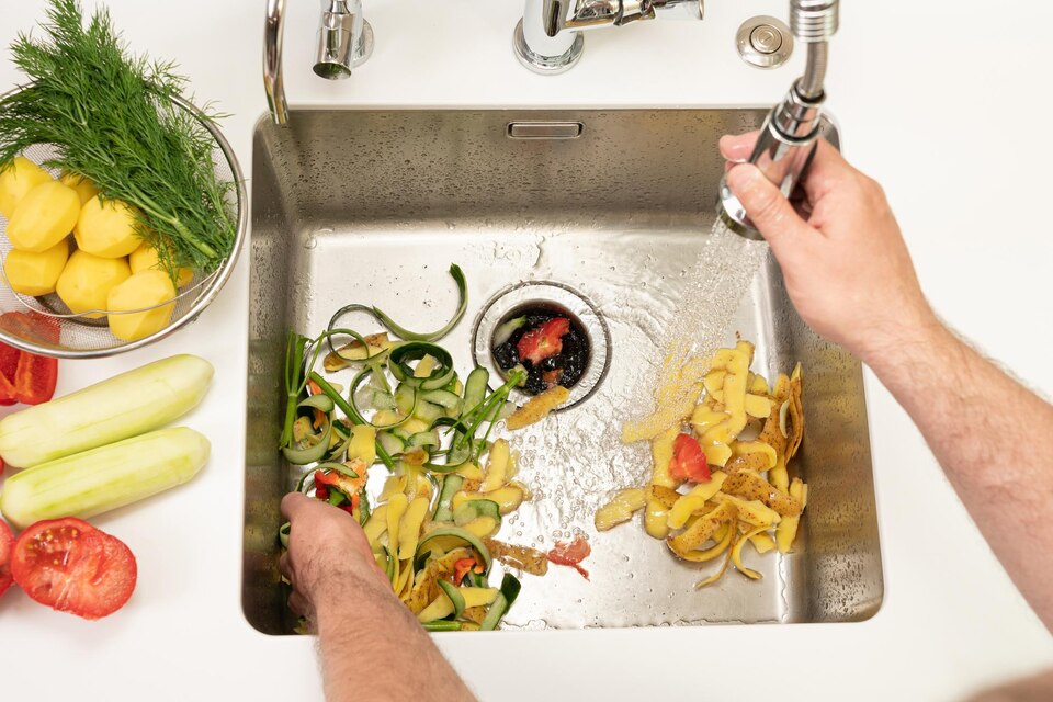 Food scraps being rinsed near a garbage disposal sink opening