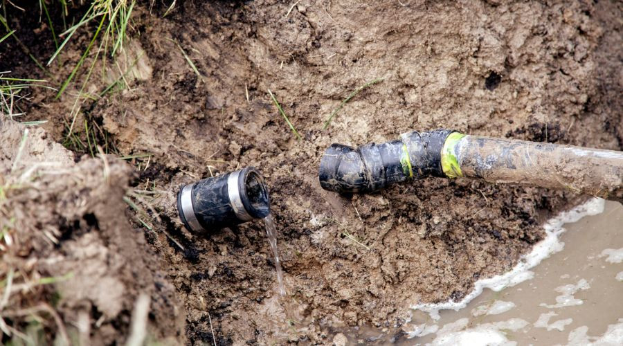 Broken underground sewer pipe with water leaking from the connection